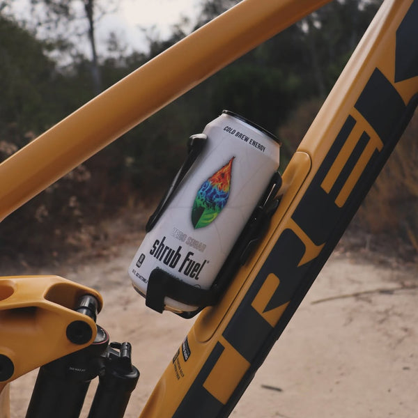 A premium 'Hero' product shot of a Shrub Fuel Guayusa energy drink can. The white matte can is set against a bold Shrub Black (#0A0A0A) background, flanked by high-definition Amazonian Guayusa leaves in Forest Green. The lighting emphasizes the vibrant flame-leaf logo and the 'Zero Sugar' messaging, creating a clean, high-contrast, and energetic aesthetic in line with the 2026 brand guidelines.