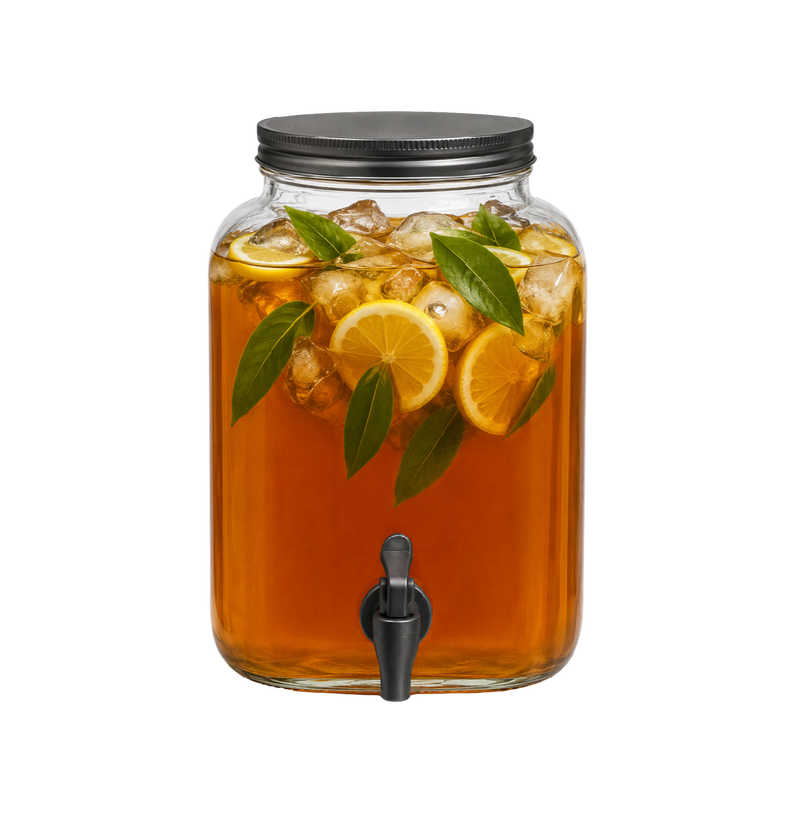 A large clear glass beverage dispenser filled with amber liquid, lemon slices, and green leaves, with a black metal lid and spout, isolated on a white background.